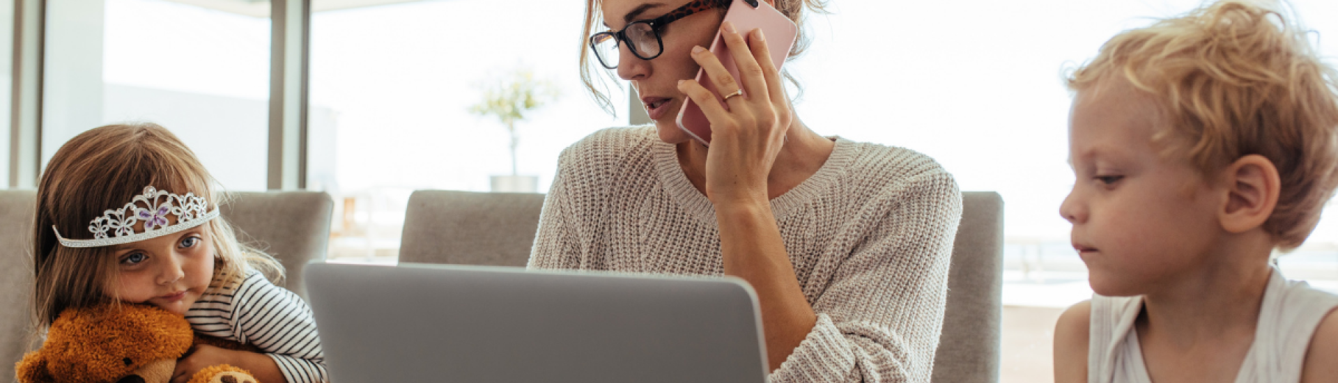 Woman working from home with 2 children beside her