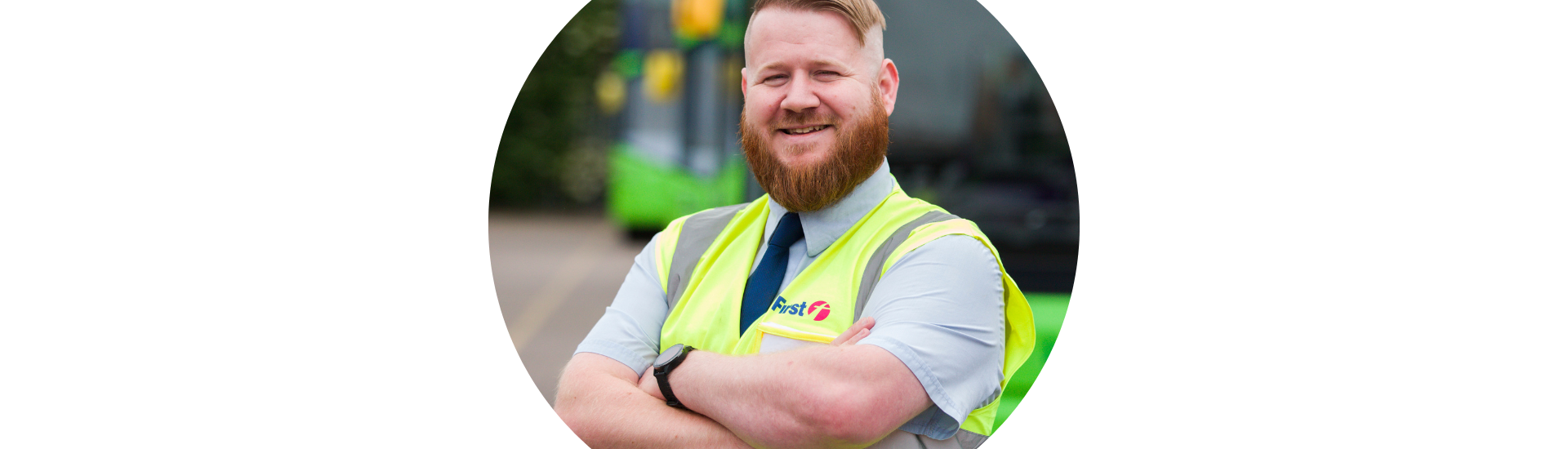 Photo of man with ginger hair standing in front of bus wearing a yellow high viz jacket. David