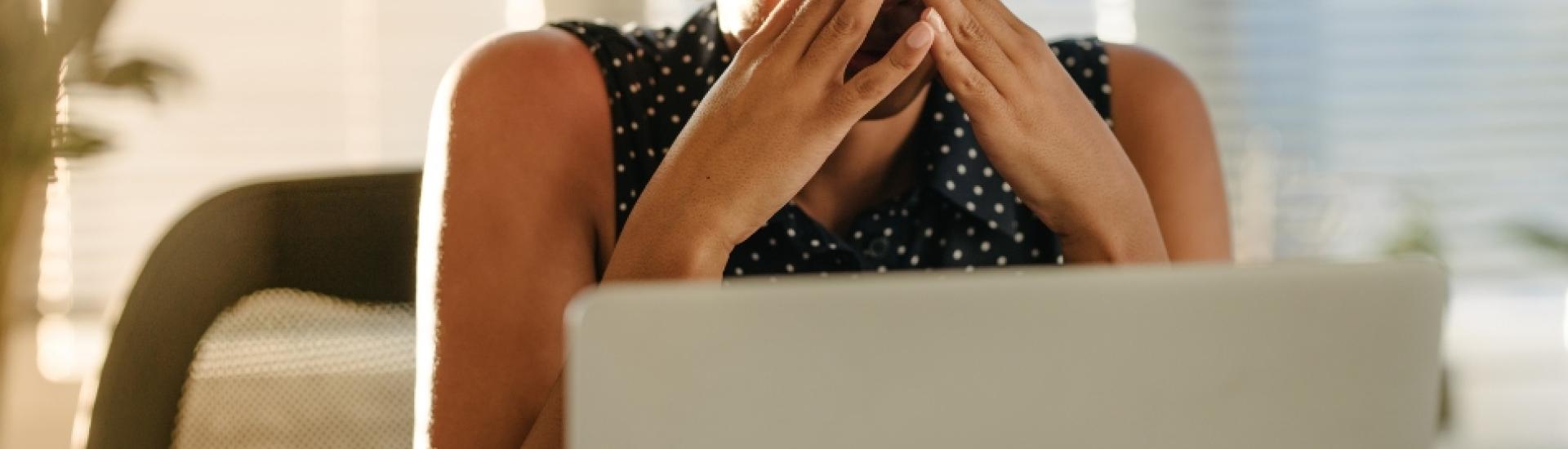 Lady with a stressed expression in front of a laptop