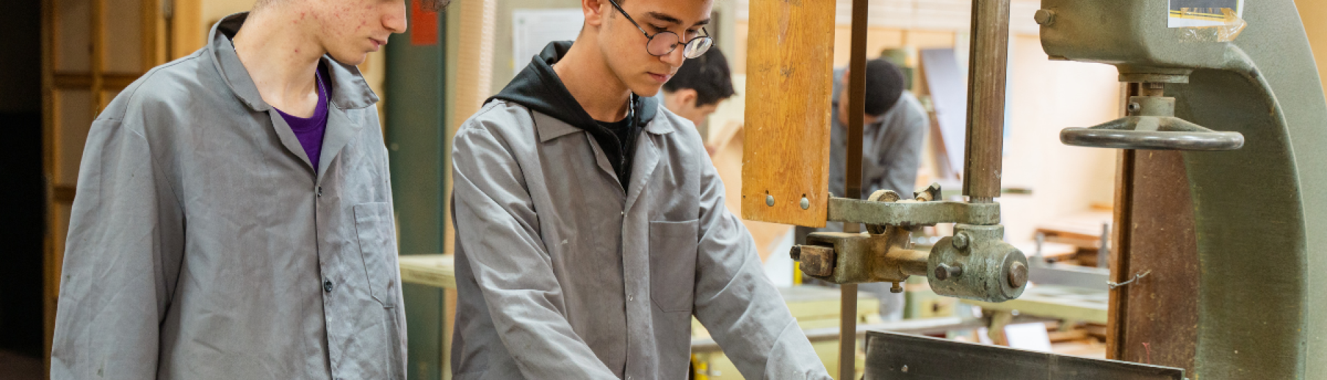 Two apprentices using a wood cutter