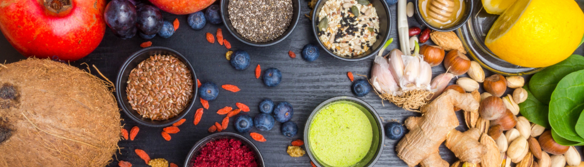 A flatlay of nutritional food: coconuts, applies, berries, nuts, lemons, yoghurts, seeds