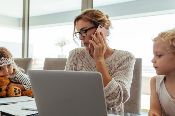 Woman working from home with 2 children beside her